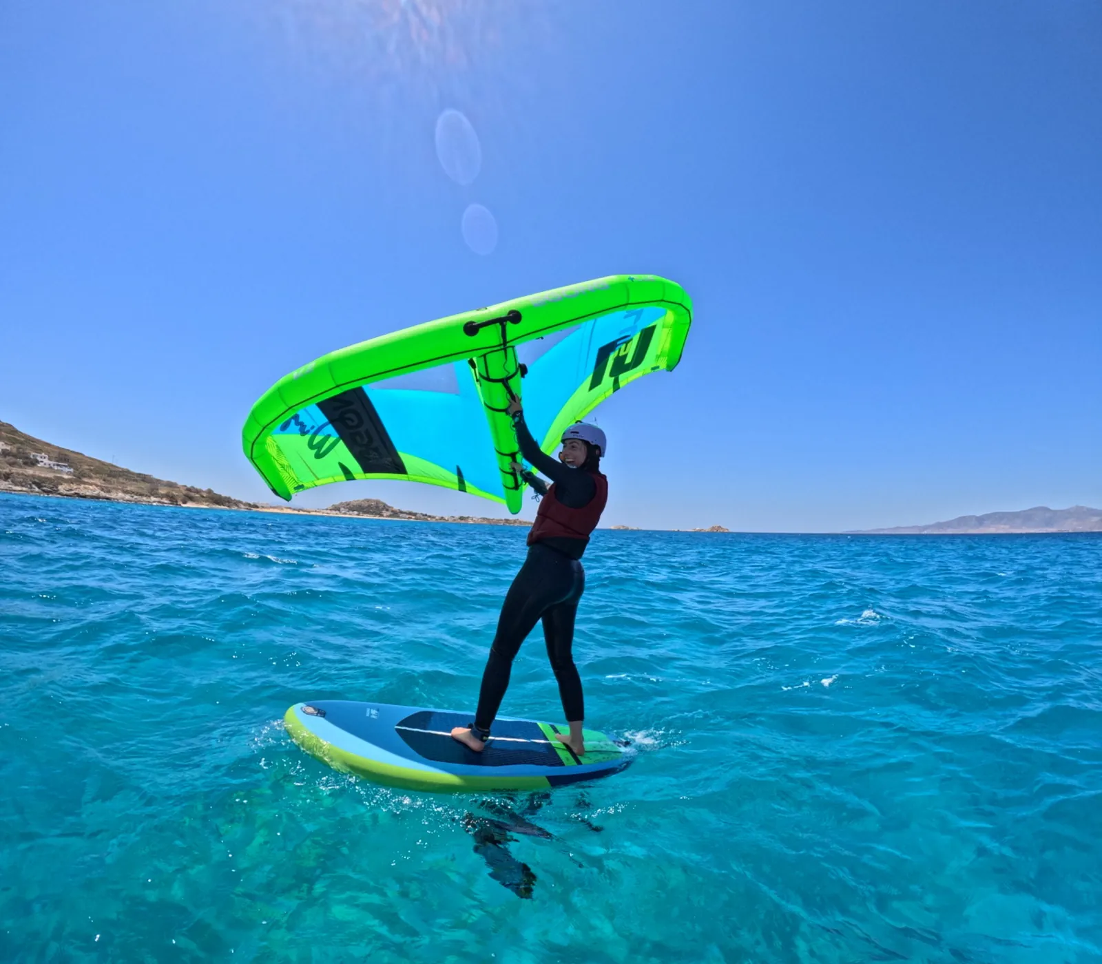 Student learning wing foiling on turquoise water during a lesson in Naxos at Plaka Beach.
